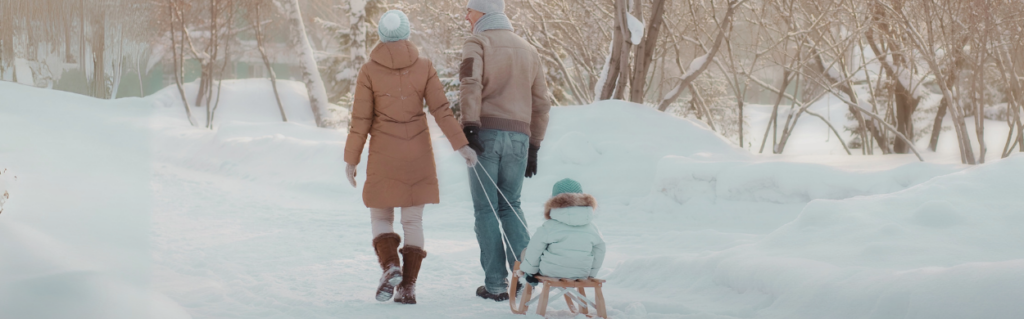 mother and father pulling child in sled